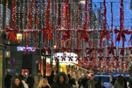 Människor på juldekorerad shoppinggata.